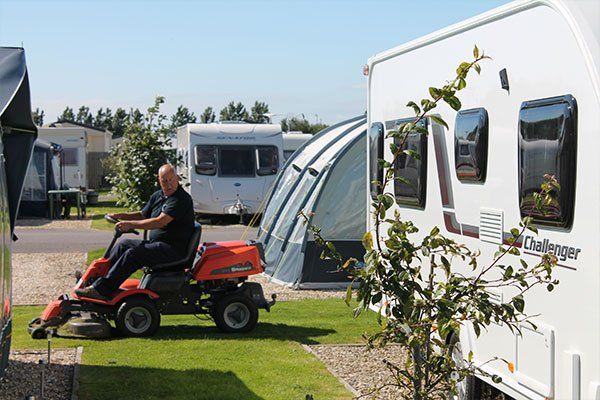 Groundsman Mowing Lawn Between Caravans at Edithmead Leisure & Park Homes