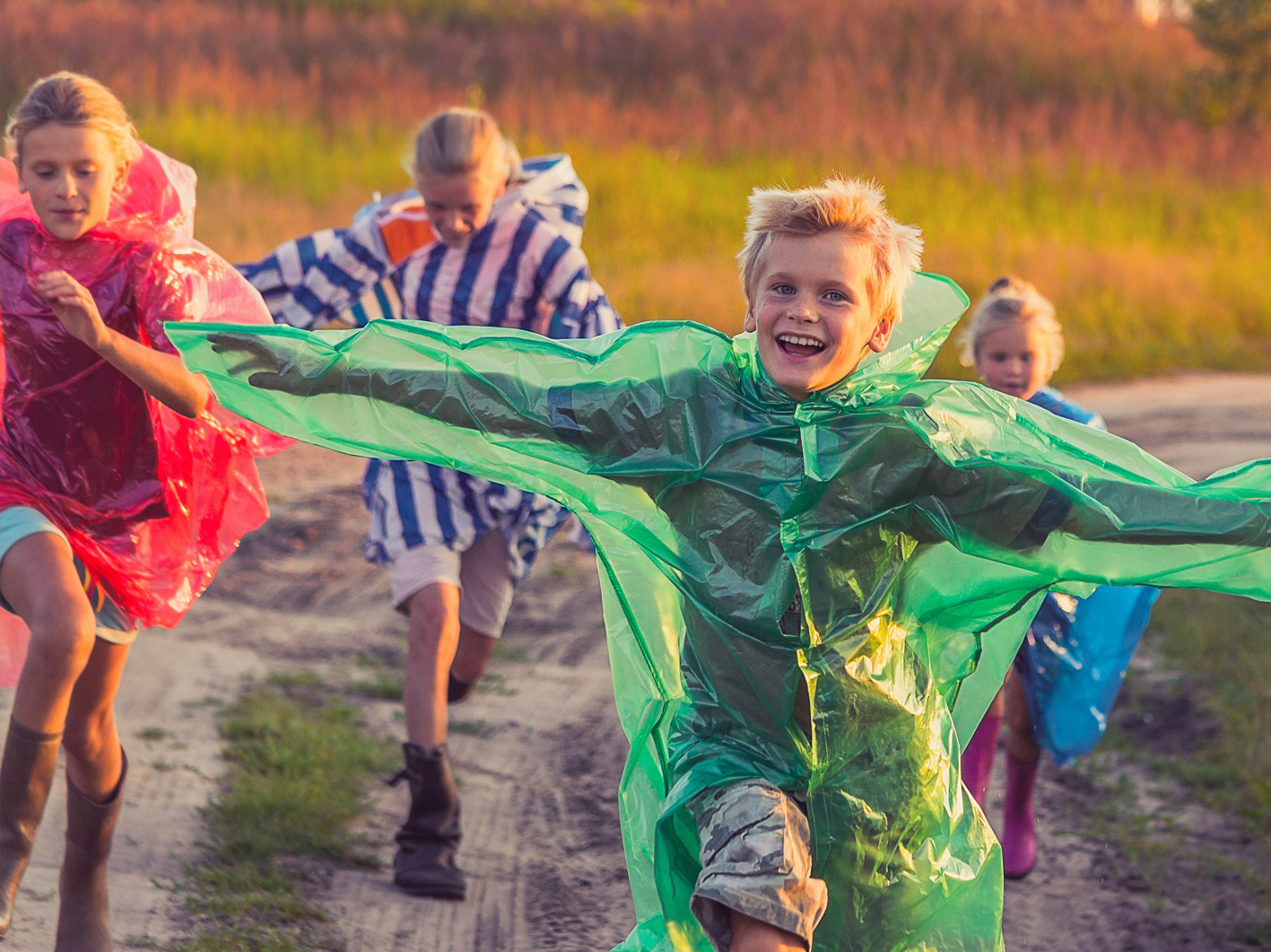 kids running in field wearing rain coats
