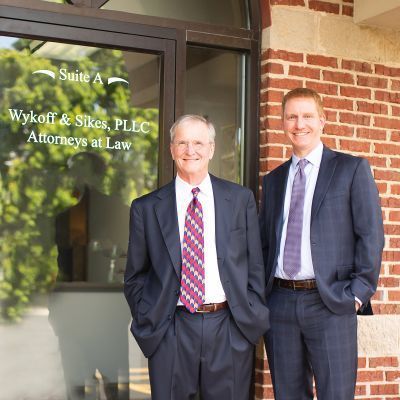 Two men in suits stand in front of a law office, 