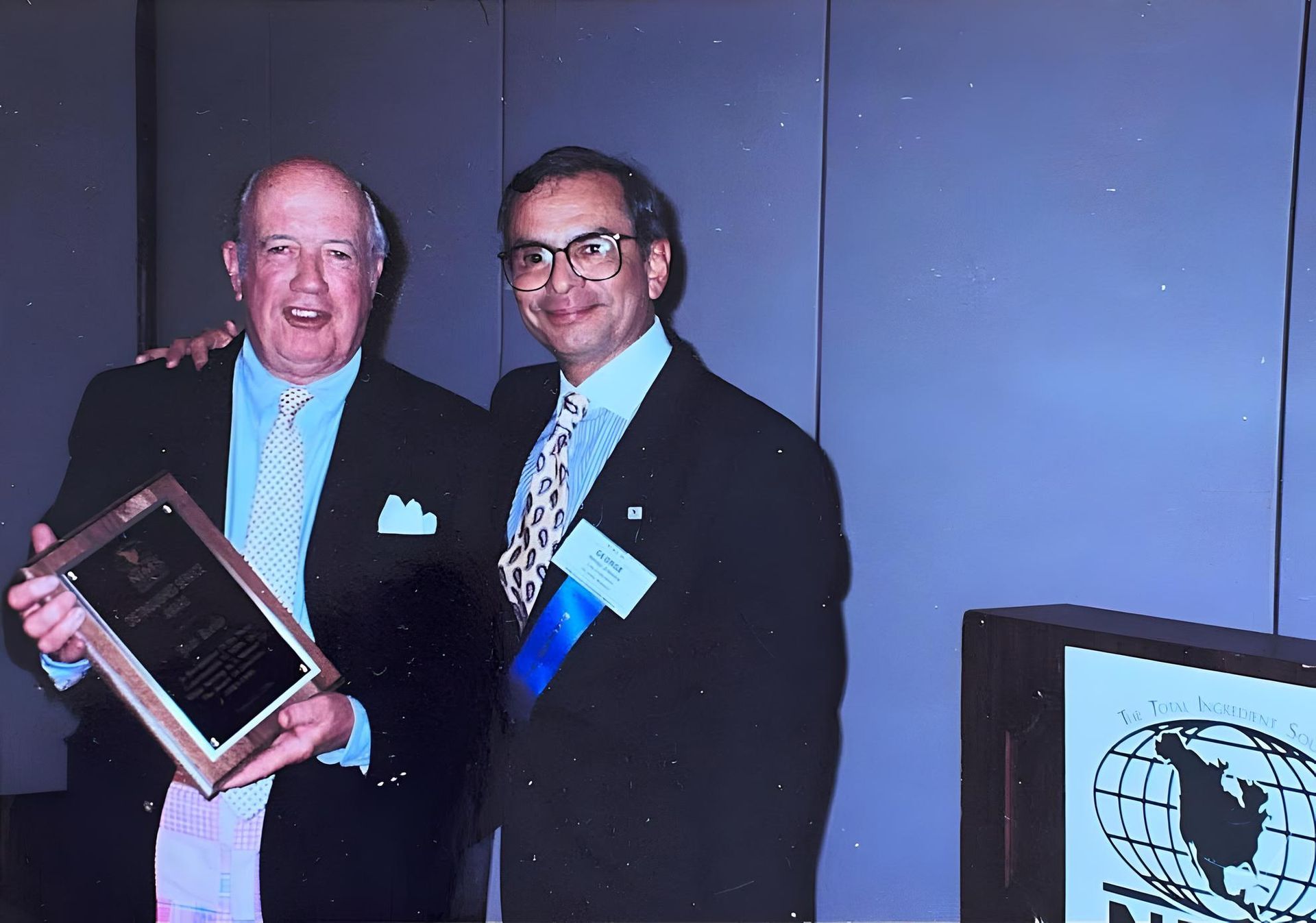 Two men standing next to each other holding a plaque at J.F. Kelly Inc. company party