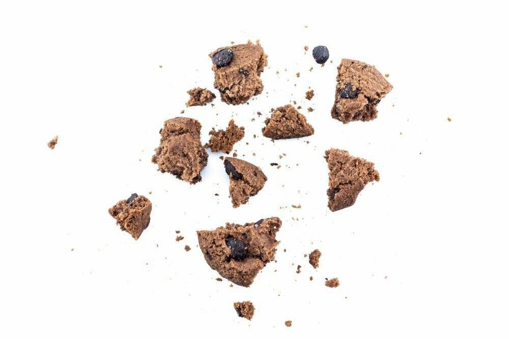 A pile of broken chocolate chip cookie dough on a white background