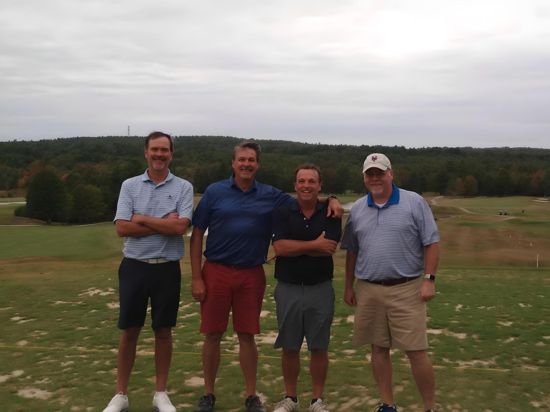 Four men are posing for a picture on a golf course