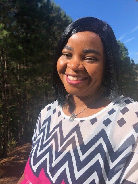 A woman wearing a chevron shirt is smiling for the camera