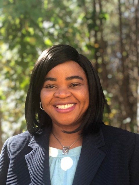 A woman in a blue jacket and blue shirt is smiling for the camera.
