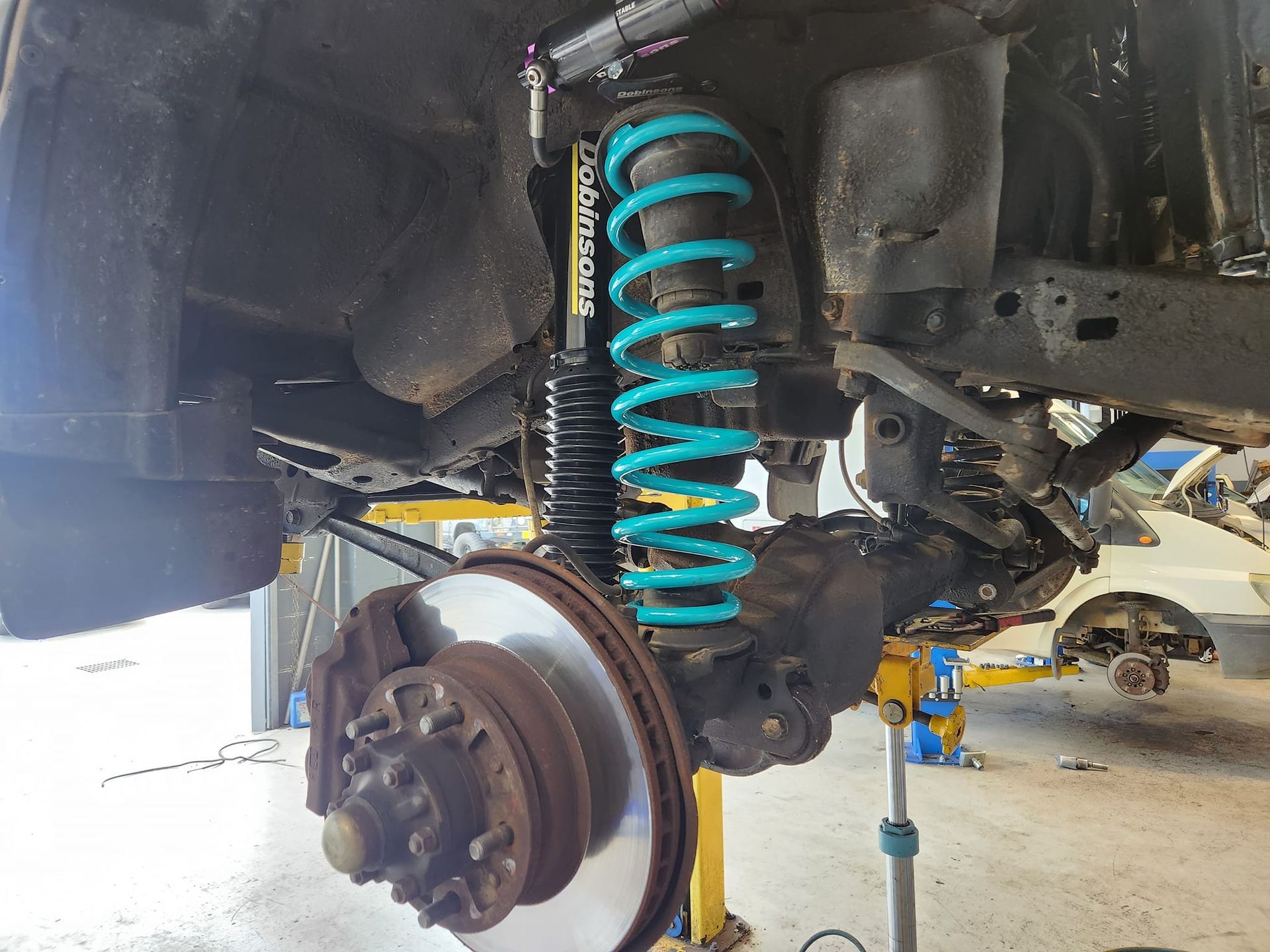 a Car's Suspension Being Worked on, With a Large Teal Spring — GZM 4x4 Performance In Ballina, NSW