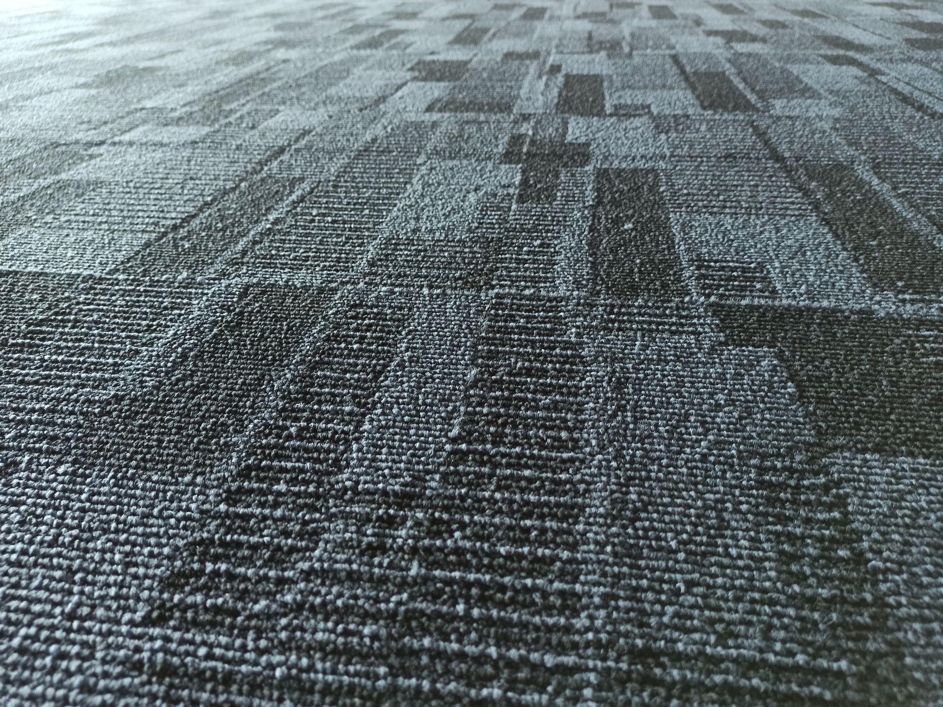 Close-up view of patterned gray carpet tiles on a floor.