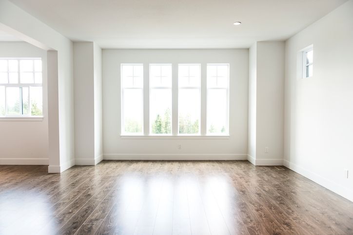 Empty room with hardwood floors, white walls, and a large window.