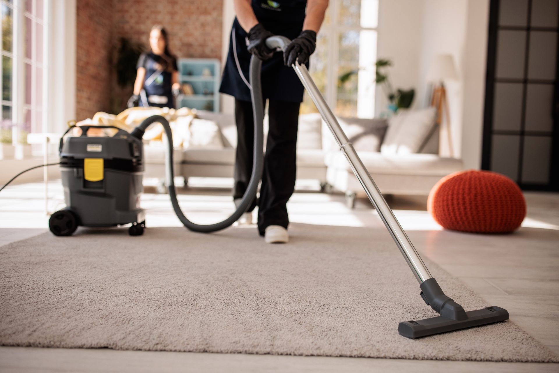 A woman is vacuuming the carpet.
