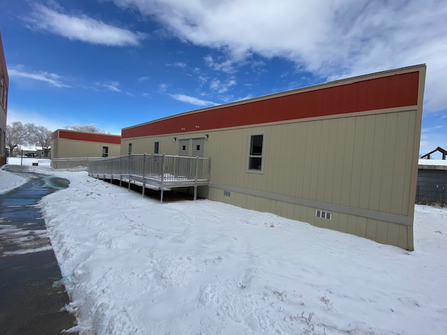 Modular school buildings, beige with red trim, snow-covered ground, wheelchair ramp.