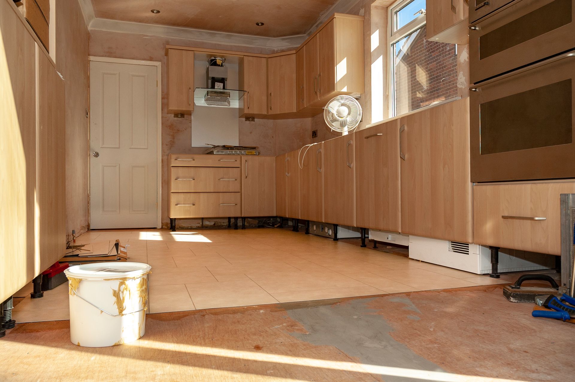 An empty kitchen with a bucket of paint on the floor - Wivenhoe, TAS - Summers Floors Pty Ltd
