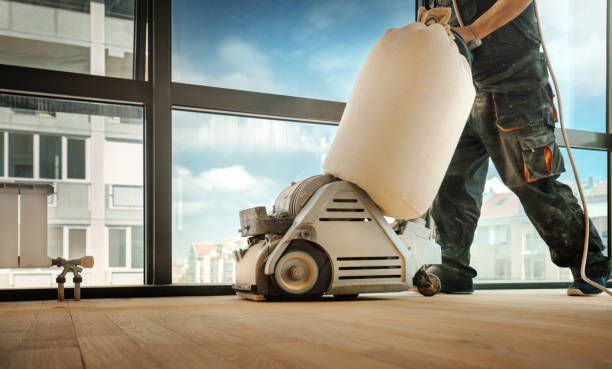 A man is sanding a wooden floor with a machine - Wivenhoe, TAS - Summers Floors Pty Ltd