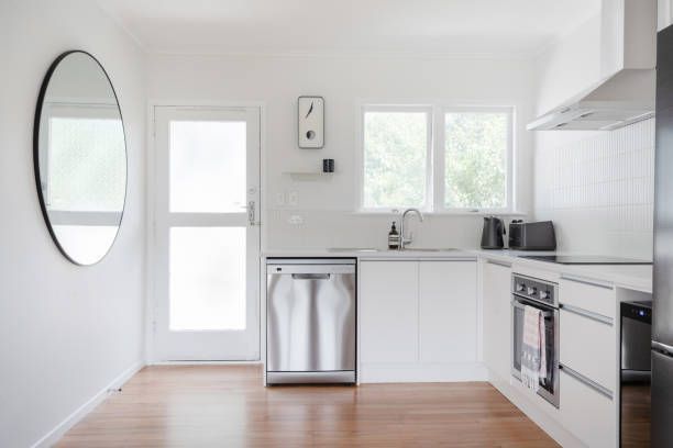 A kitchen with white cabinets, stainless steel appliances, and a round mirror - Wivenhoe, TAS - Summers Floors Pty Ltd
