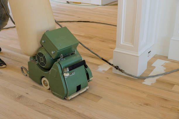 A person is sanding a wooden floor with a machine - Wivenhoe, TAS - Summers Floors Pty Ltd
