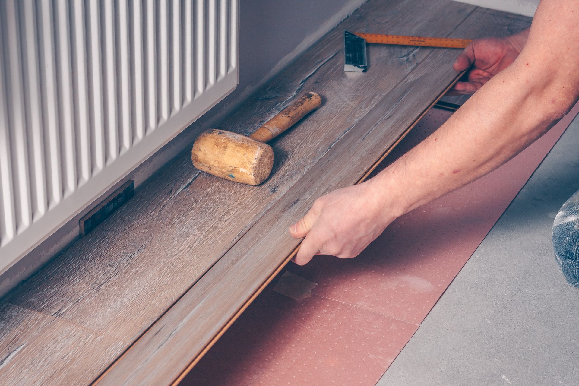 A man is installing a wooden floor in a room - Wivenhoe, TAS - Summers Floors Pty Ltd