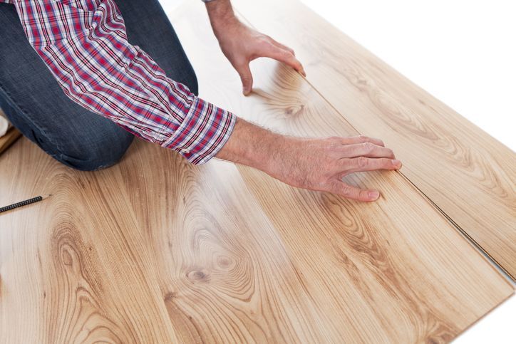 A man is kneeling down to install a wooden floor - Wivenhoe, TAS - Summers Floors Pty Ltd