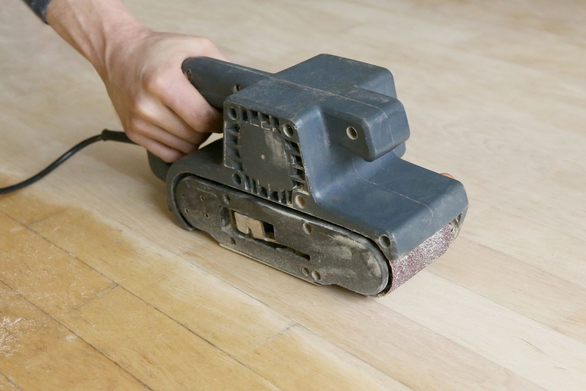 A person is sanding a wooden floor with a sander - Wivenhoe, TAS - Summers Floors Pty Ltd