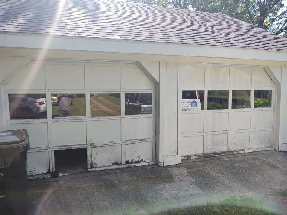 A white garage door with a broken window and a truck parked in front of it.