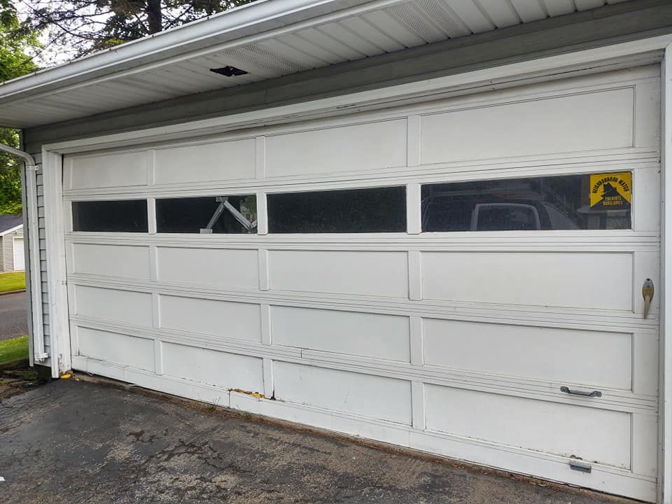 A white garage door with a yellow warning sign on it.