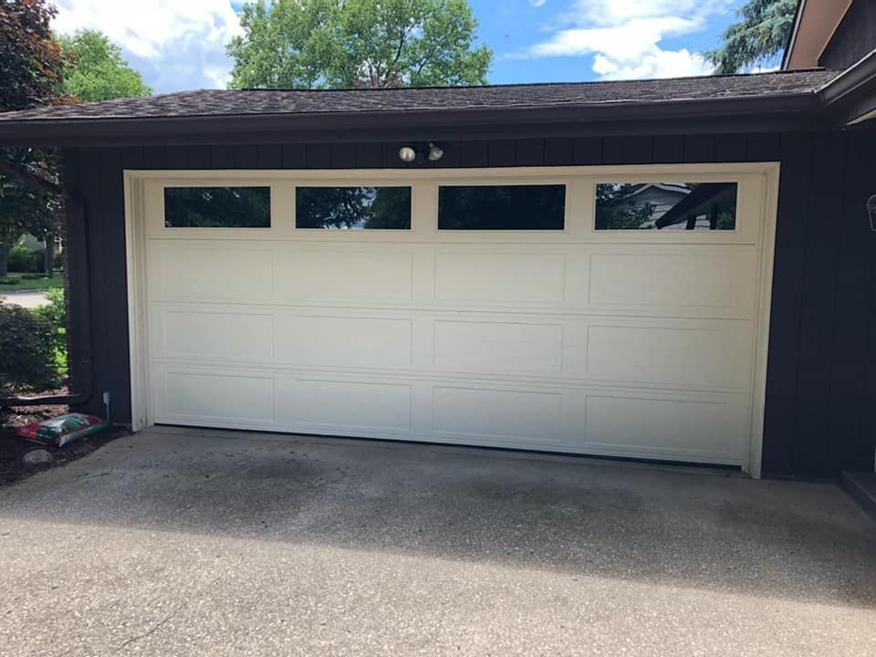 A white garage door is sitting in the driveway of a house.