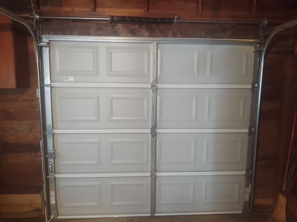 A white garage door is open in a garage.