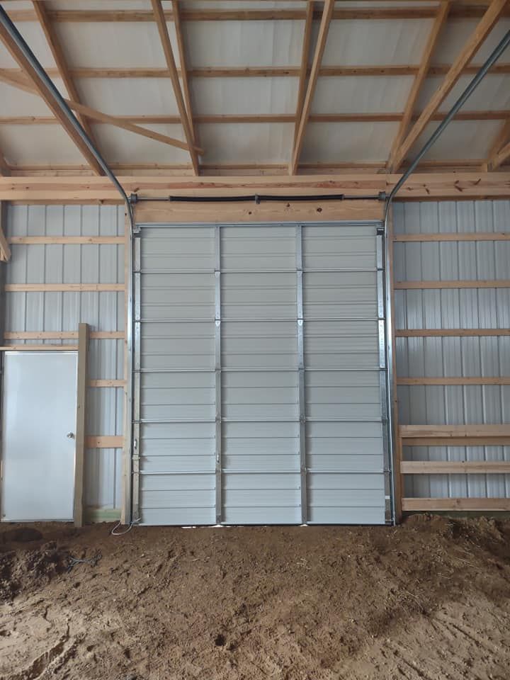 A white garage door is open in a wooden building.