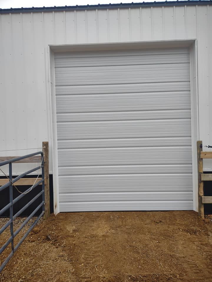 A white garage door is sitting in front of a white building.