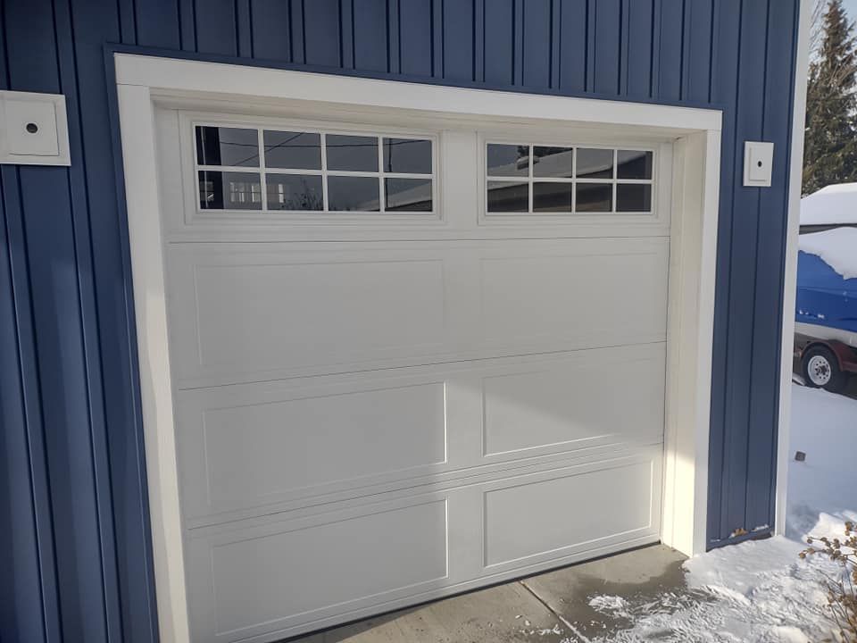 A white garage door is sitting in front of a blue building.