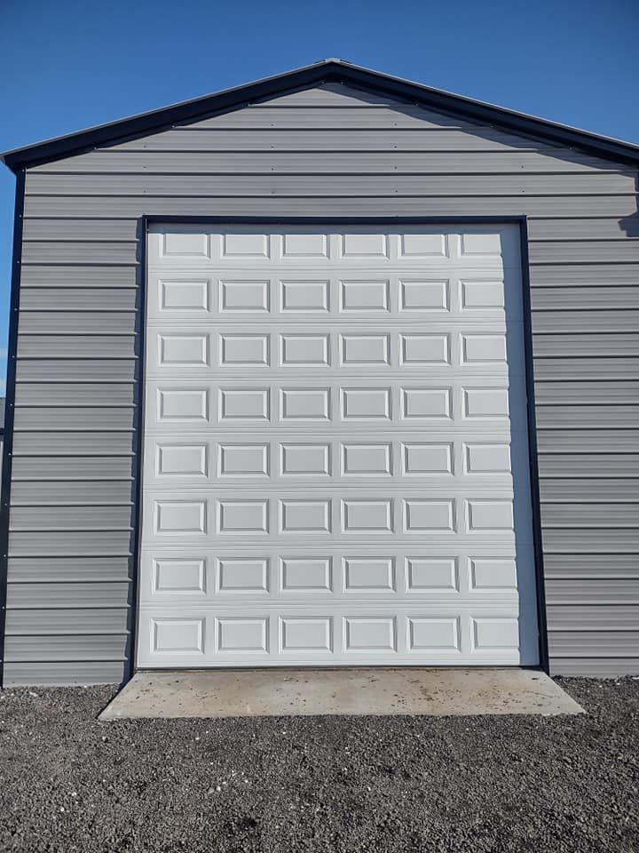 A white garage door is open on a gray building.