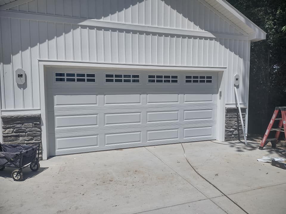 A white garage door with a black wagon parked in front of it.