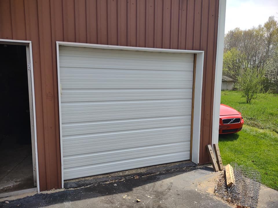 A red car is parked in front of a garage door.