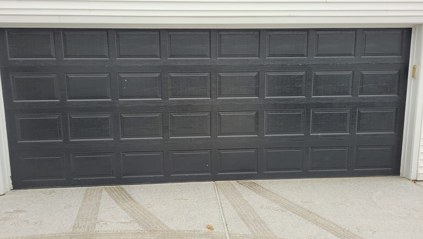 A black garage door is sitting on the side of a house.