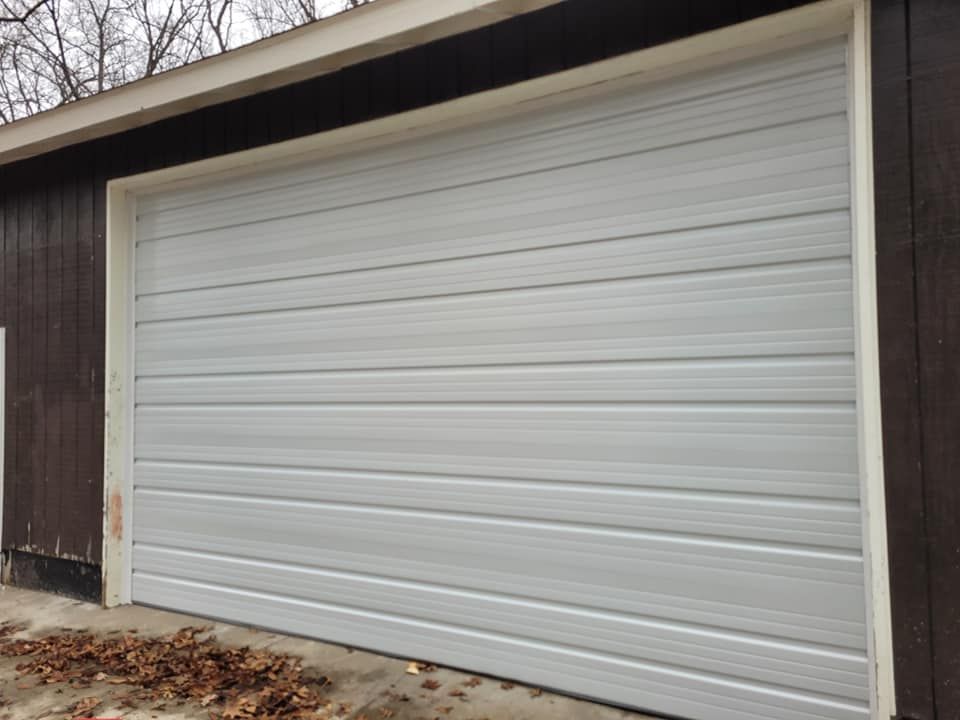 A white garage door is on a brown building.