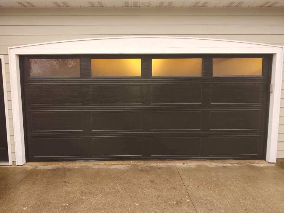 A black garage door with a yellow light inside of it.