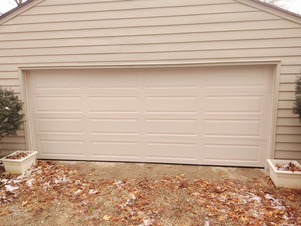 A white garage door is sitting in front of a house.