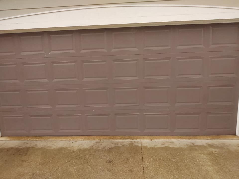 A purple garage door is sitting on top of a concrete driveway.