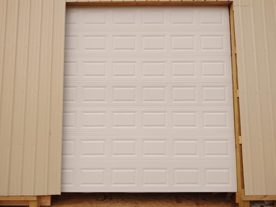 A white garage door is being installed on the side of a building.