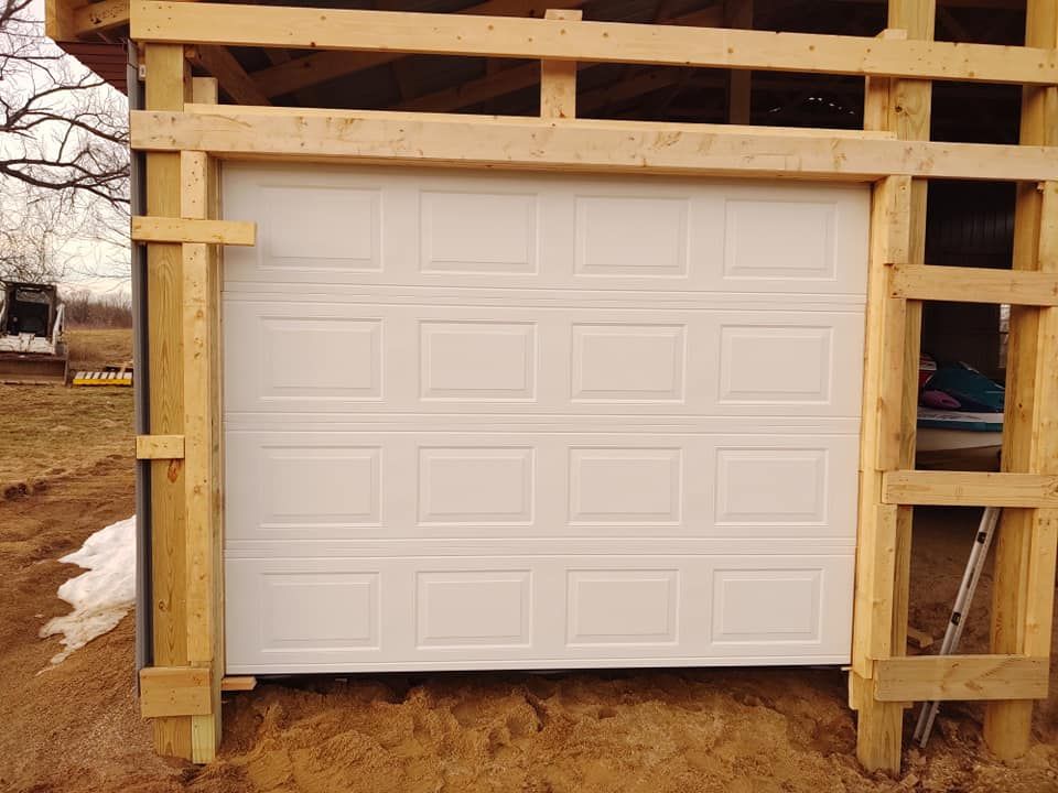 A white garage door is being built into a wooden structure.