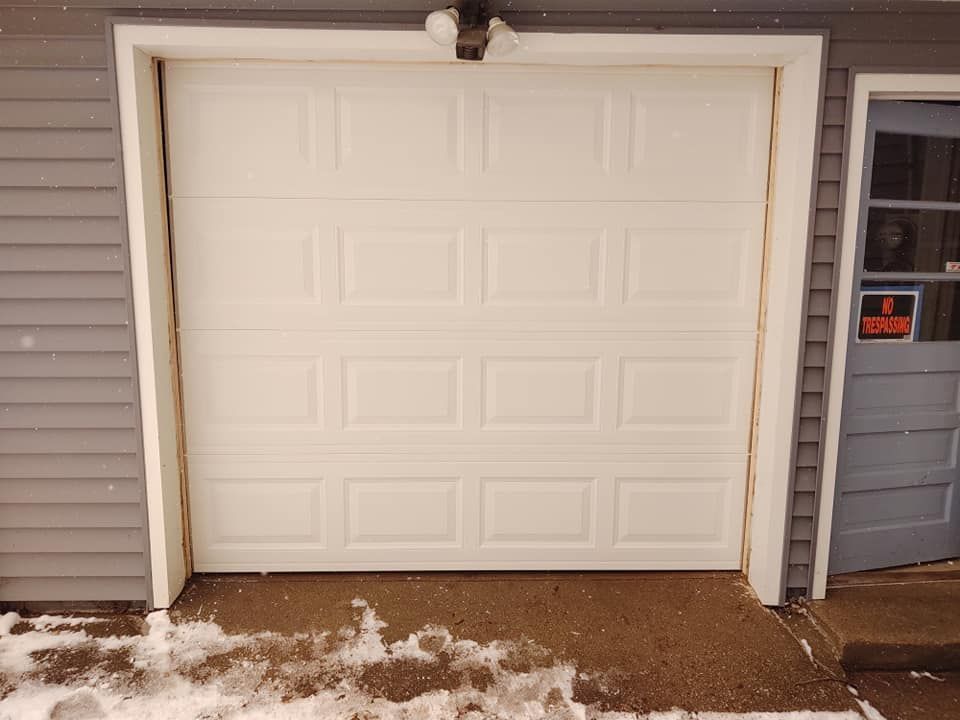 A white garage door is open in front of a house