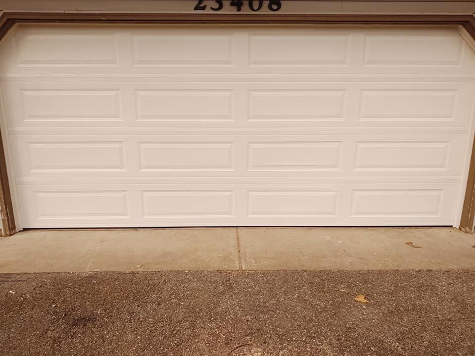 A white garage door is open to a driveway.