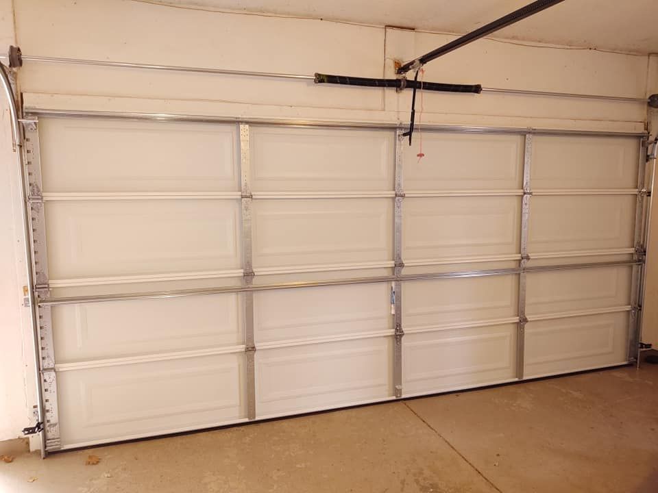 A white garage door is open in a garage.