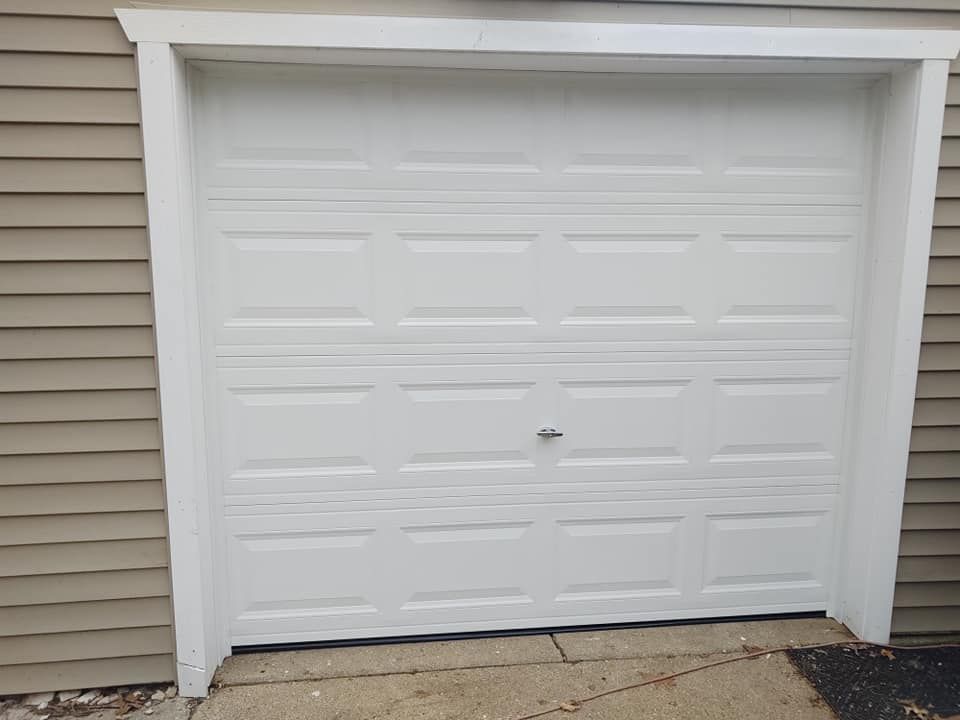 A white garage door is sitting on the side of a house.