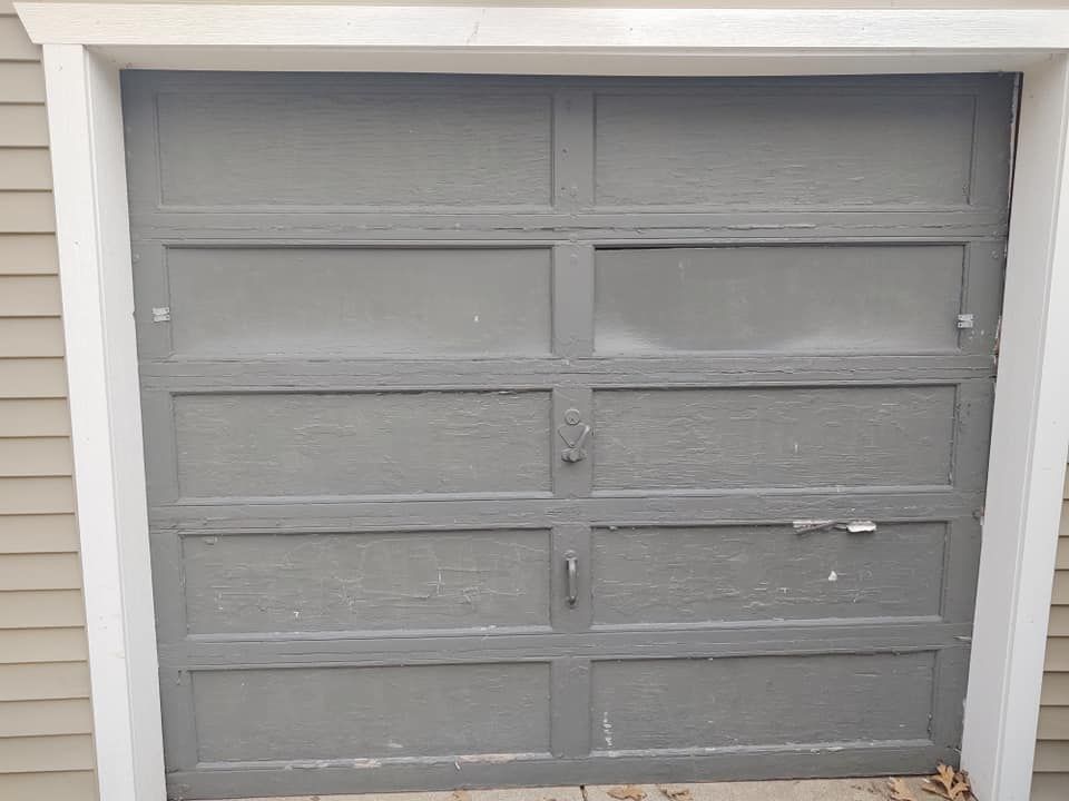 A gray garage door is sitting on the side of a house.