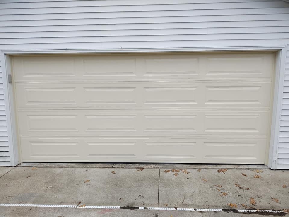 A white garage door is sitting on the side of a house.