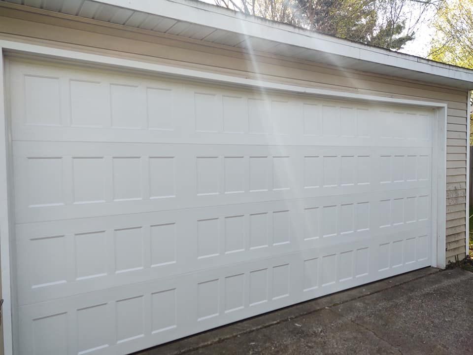 A white garage door is sitting on the side of a house.