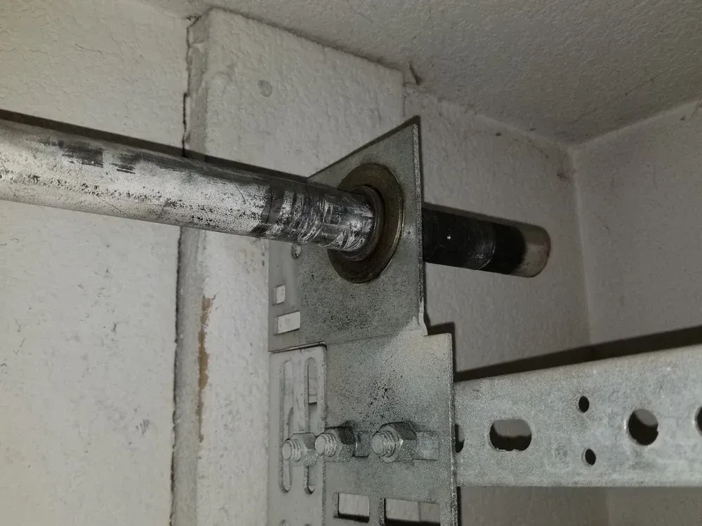 A close up of a garage door spring on a wall.