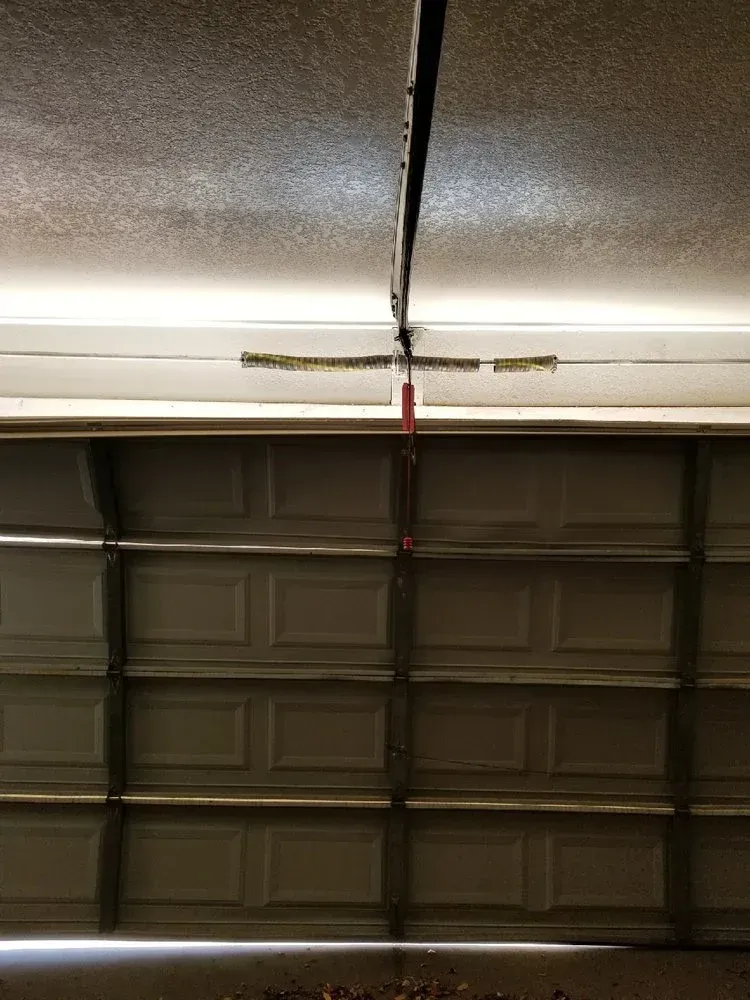 A close up of a garage door with a broken hinge.