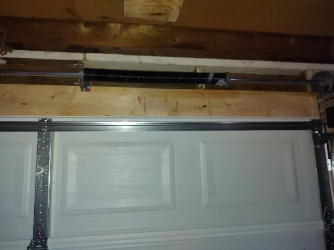 A close up of a garage door with a spring in it.