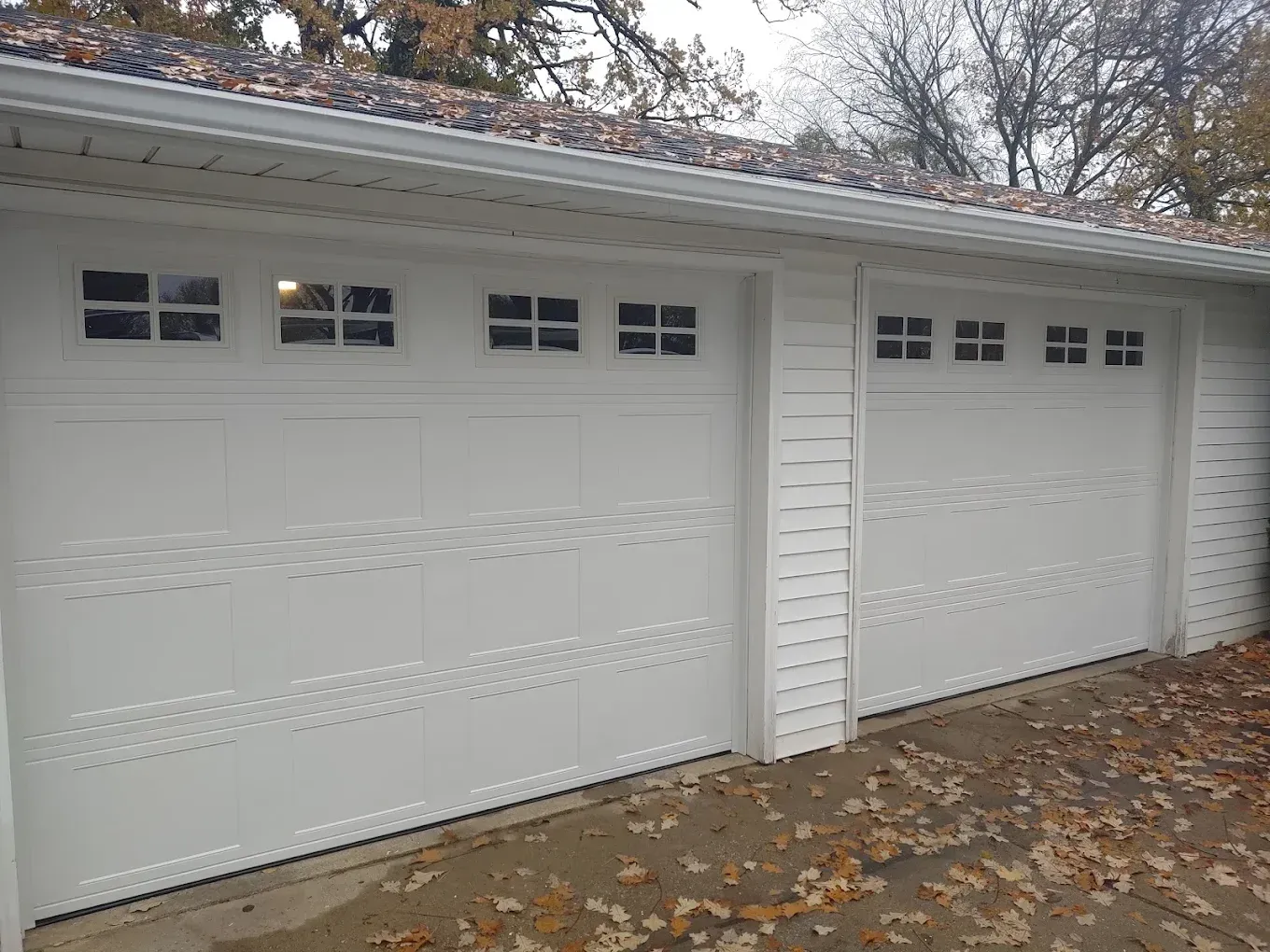 Three white garage doors with windows on a house.