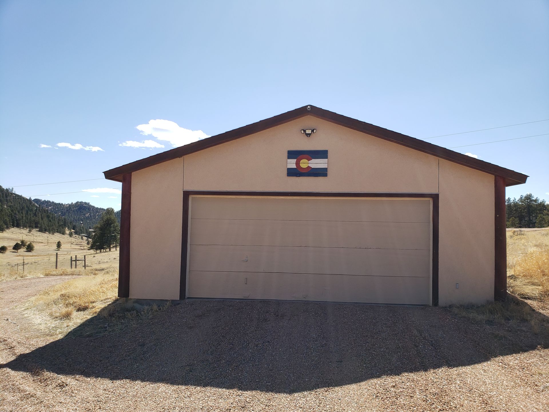 Garage with Colorado flag on the front, set in a rural landscape under a blue sky.