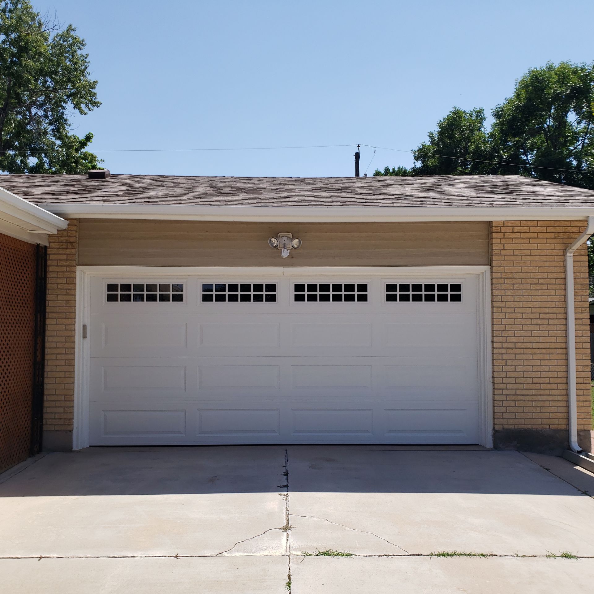 White garage door with windows, on a tan and brick garage. Concrete driveway in front.